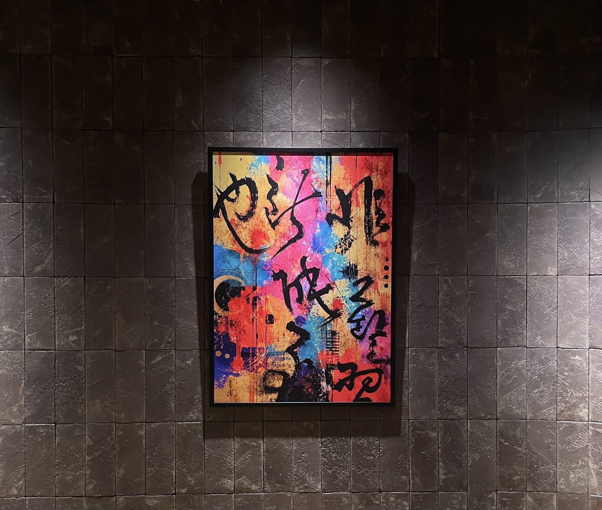 額装された作品。金地に朱・藍・桃の色面が重なり、その上を黒い筆の線が走る