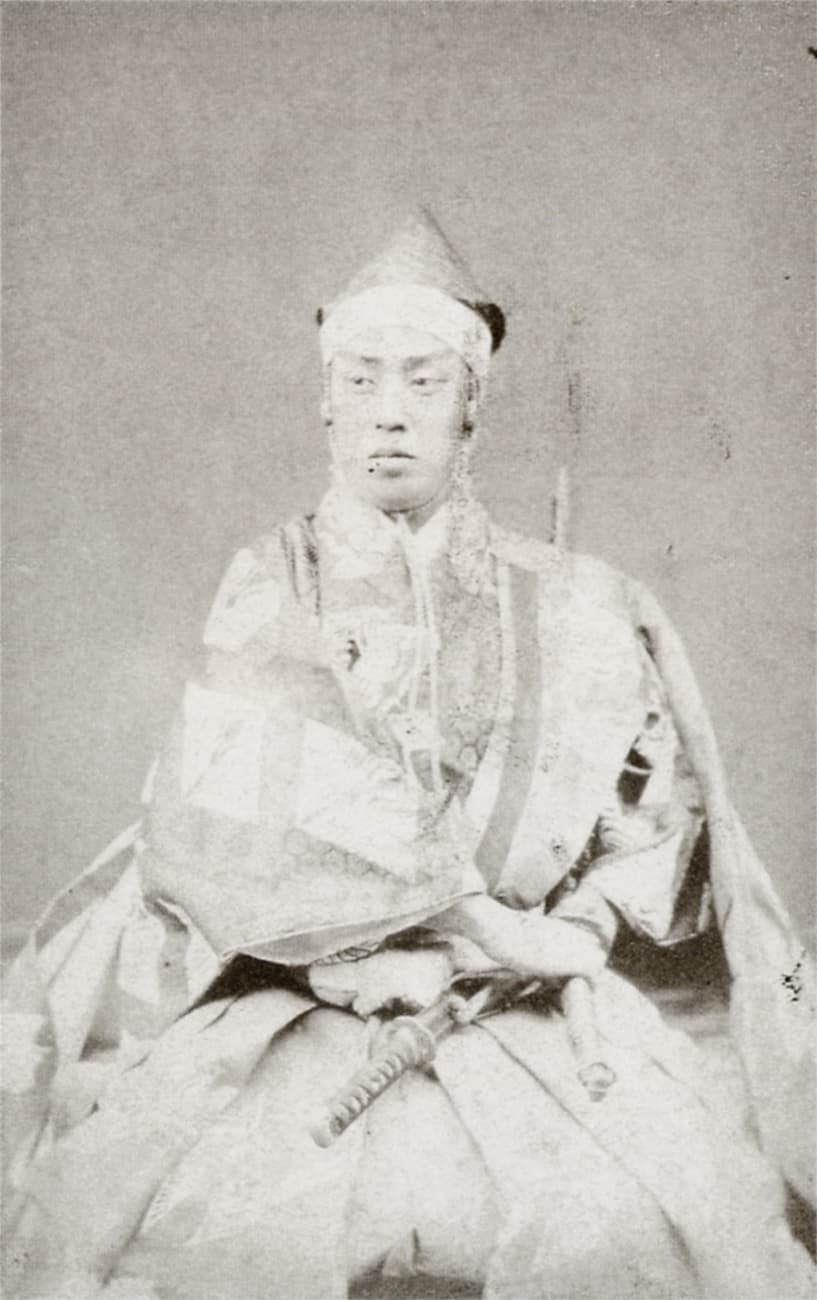 九代目市川團十郎の古写真。烏帽子をかぶり紋付の直垂をまとって正座し、傍らに太刀を置いて正面を見据える姿